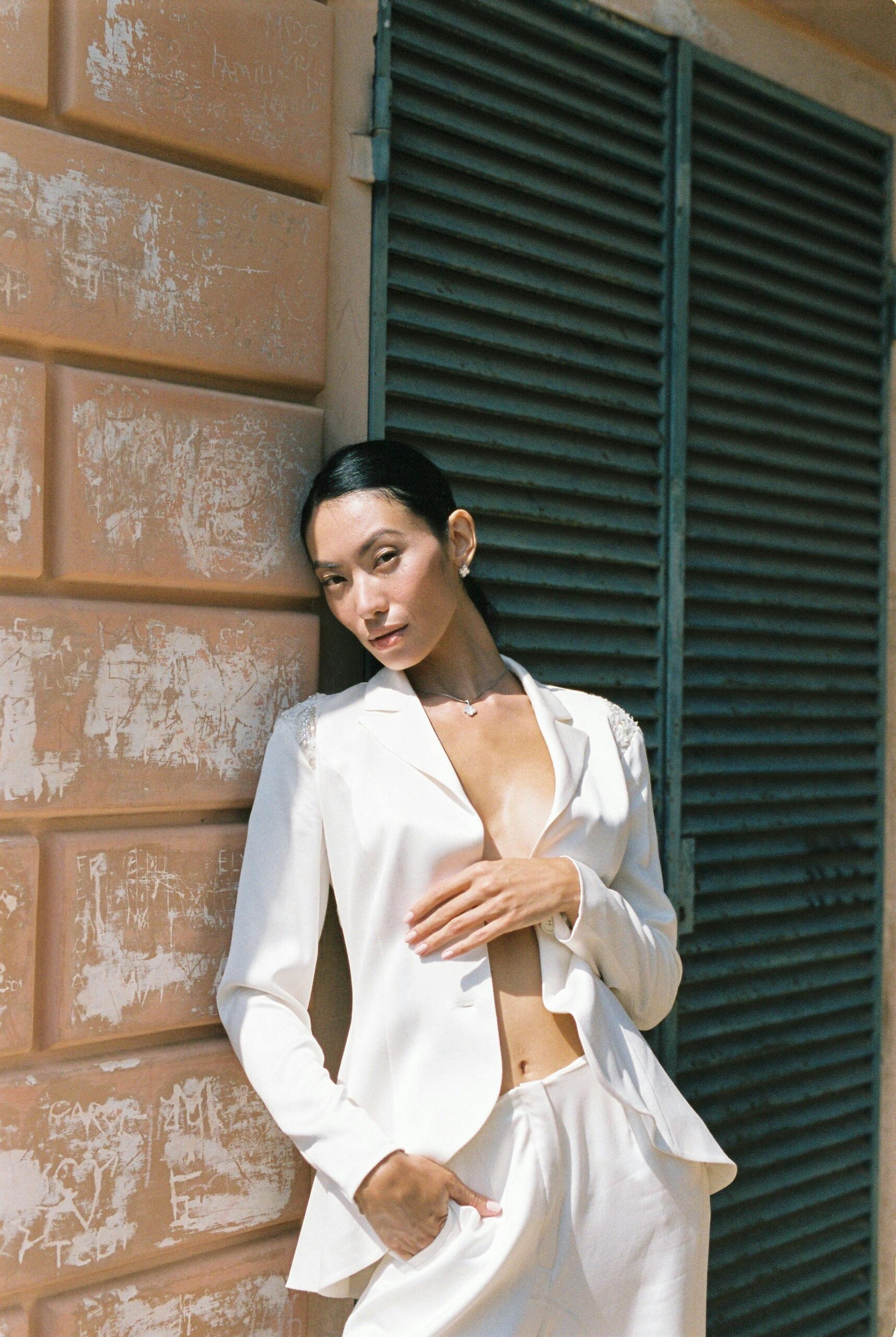 Woman in White Blazer Standing Beside Brick Wall